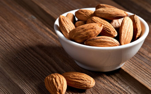 Close up almonds in white sauce pan on wooden table