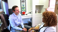 A guy in blue shirt is talking to a dentist about the dental care