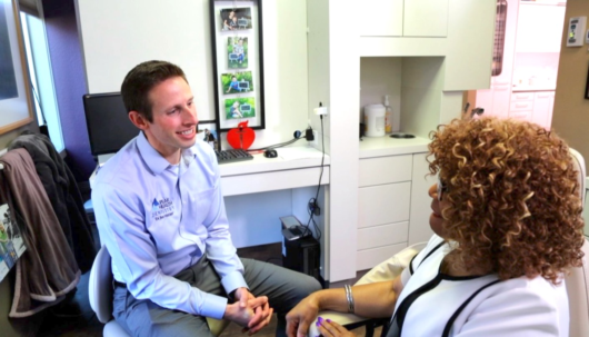 A guy in blue shirt is talking to a dentist about the dental care