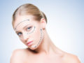 A close up photo of the beautiful girl on the blue background that shows the results of the facelift procedure. Young face without signs of aging
