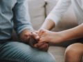 A girl is holding a man's hand to help him cope with grief