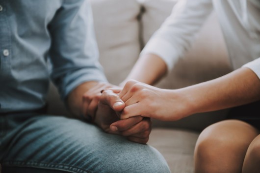 A girl is holding a man's hand to help him cope with grief