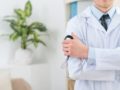 A doctor's torso in a white robe. He is holding stethoscope