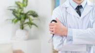 A doctor's torso in a white robe. He is holding stethoscope