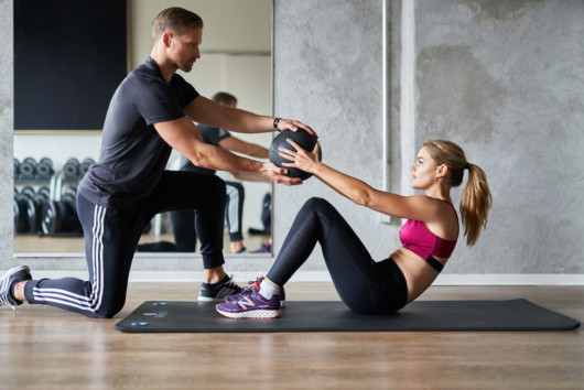 A personal trainer is working out with the girl in the gym