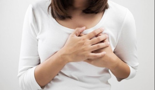 An isolated picture of the girl in white blouse on white who is holding her breasts with two hands