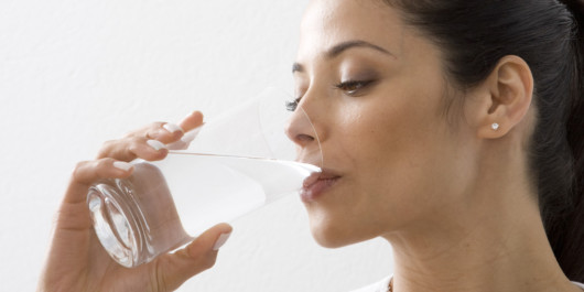 Girl isolated on white drinking water from the glass