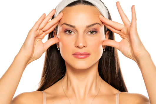 A beautiful girl on white background touching her face with fingers