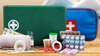 Blue and green first aid kit with pills and different supplies on wooden background