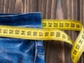 jeans with a tape measure on wooden background