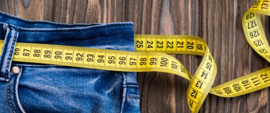 jeans with a tape measure on wooden background