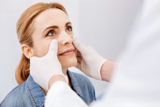 A doctor is checking woman's face before the plastic or cosmetic surgery 