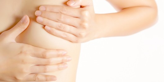 A close up picture of the girl's breast covered with the hands on white background