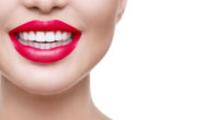 A close up picture of a girls mouth on white with red lipstick and perfect white teeth