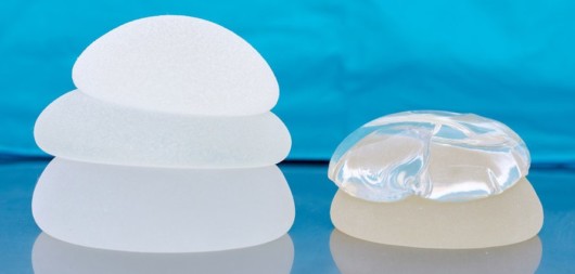 Different types of breast implants are lying on the blue background