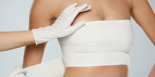 A close up photo of girl's breast in a bandage after the breast augmentation procedure