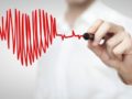 A doctor is drawing a red heart with a pen in front of him