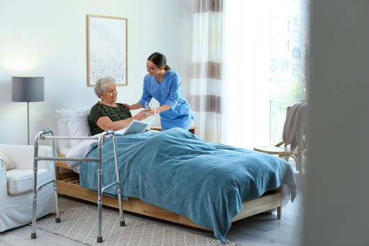 A nurse is helping an old lady and giving her water in hospice