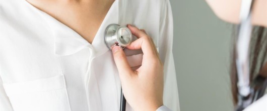 A doctor is using stethoscope to hear the girl's heartbeat