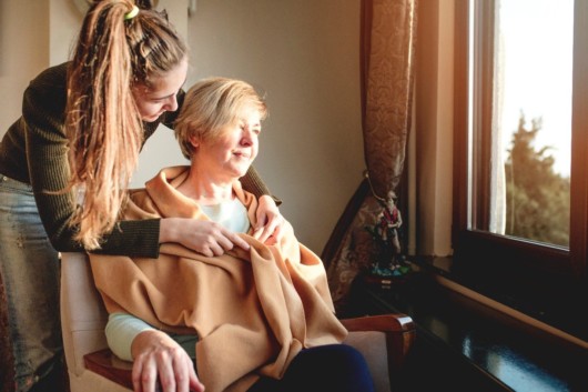 A young lady is taking care of an old woman in a hospice