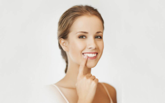 A close up photo of the girl isolated on white who is pointing at her teeth with her finger