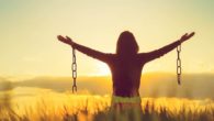 A young girl is staying with her arms spread to the sites welcoming the sunrise