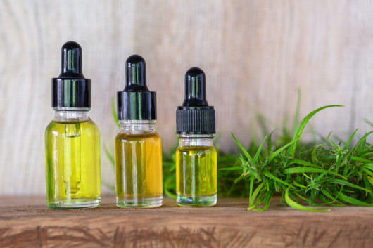 CBD oil in bottles and hemp leaves on the wooden background