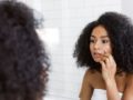 A young and beautiful girl looking in to the mirror and checking her skin for wrinkles