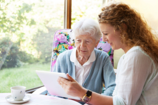 Young girl is showing something to an old woman and choosing an aged care home