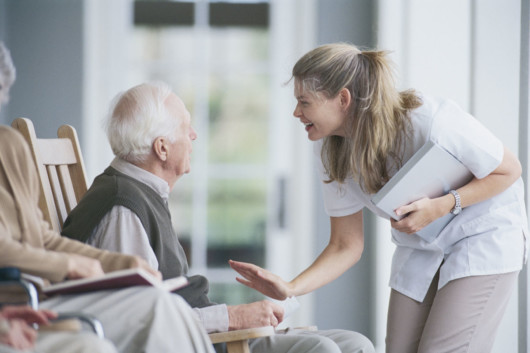 Caretaker is talking nicely to an old man in an aged care home 