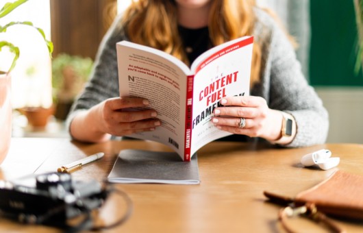 A girl is sitting at the table and reading a book