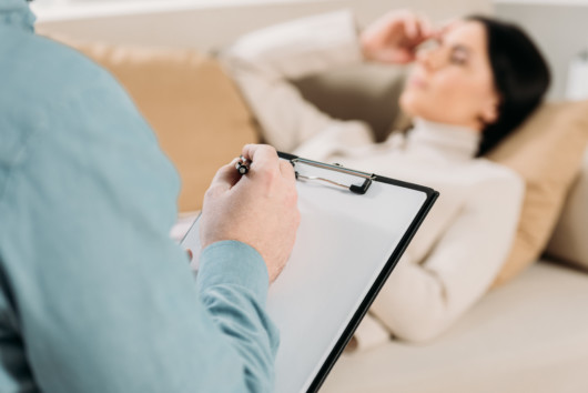 A girl is lying on the coach during hypnotherapy