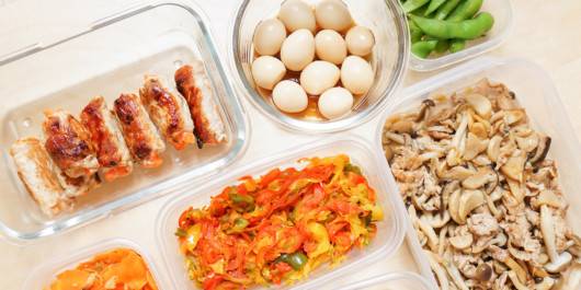 Boiled eggs, meat, salads are in different plates on white background