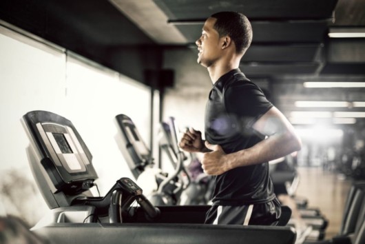 Guy is running on the treadmill in the gym