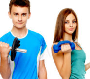 Teenage girl and a boy on the white background holding dumbbells