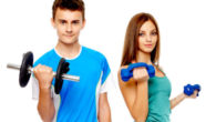 Teenage girl and a boy on the white background holding dumbbells