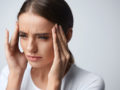 Girl is keeping her fingers at the temples due to a severe headache