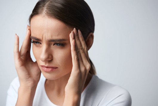 Girl is keeping her fingers at the temples due to a severe headache