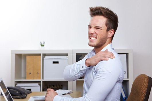 Guy writhing with pain holding his shoulder