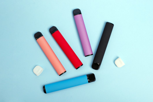 Disposal cbd vape pen of different colors are on the blue background
