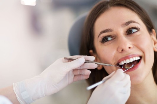 A doctor is checking a young woman's teeth at the dental checkup