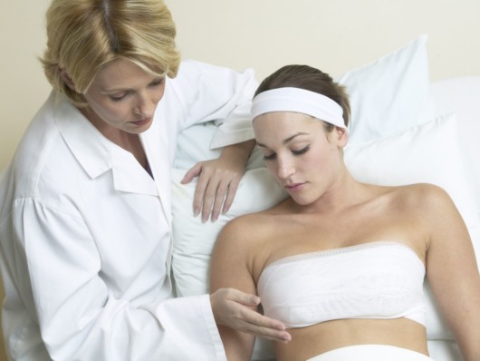 A doctor is checking girls breast after the breast augmentation procedure