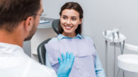 A smiling girl is at the dental checkup talking to the doctor