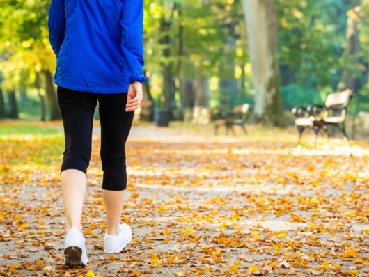 Girl in blue jacket is walking in the park in autumn