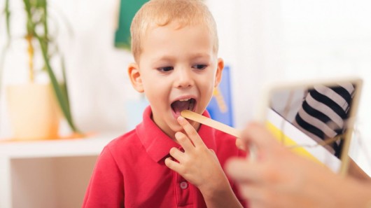 A little boy is being checked by the speech doctor