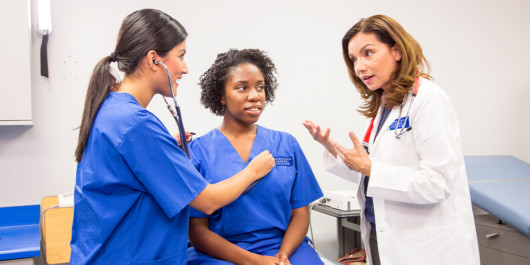 A doctor is teaching a young medical assistant how to treat a patient