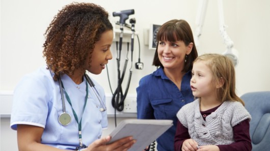 Young medical assistant is consulting a woman and her daughter in the clinic