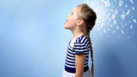 a little girl in a blue stripped dress is standing with her mouth open on the blue background with white letters behind her