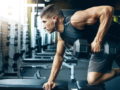 A strong and physically developed guy is exercising in the gym with a dumbbell