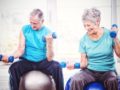 Senior people are doing exercises on the fitness balls with dumbbells